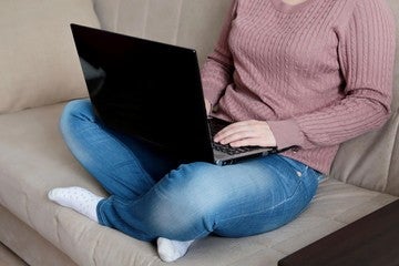 woman sitting cross legged on couch working on laptop